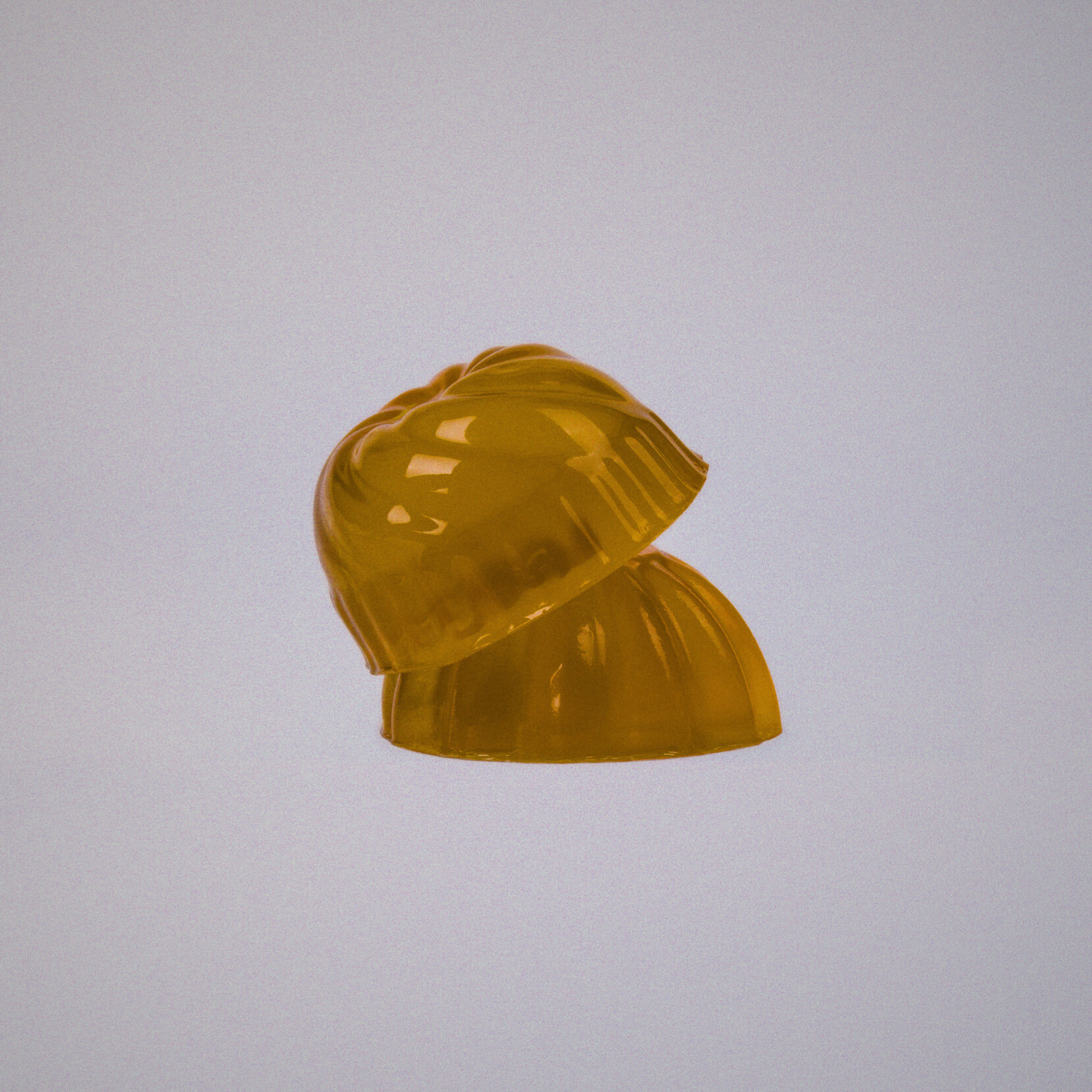 Two yellow gelatin cups stacked on top of each other on a light grey background