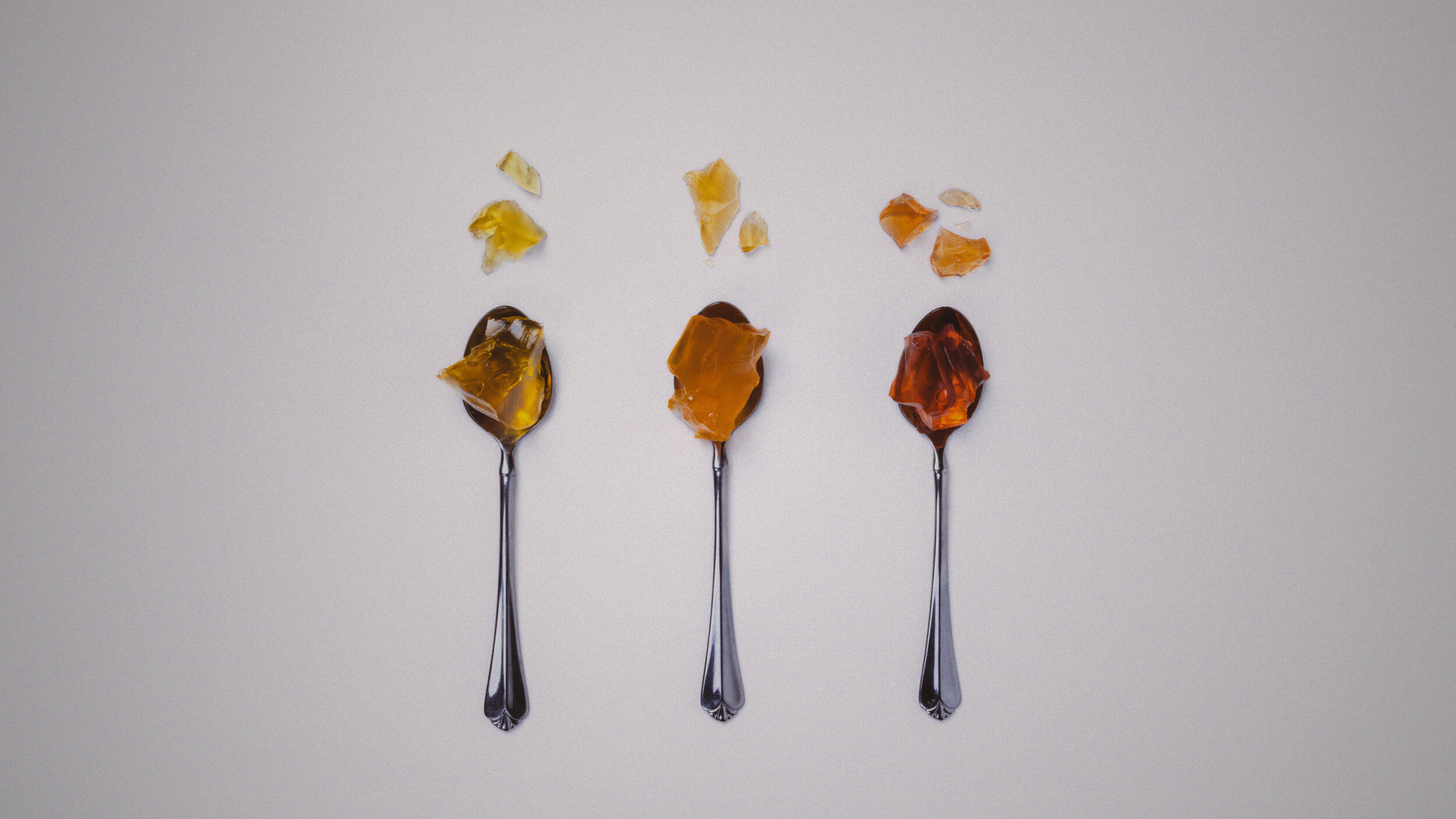 Three spoons with different gelatin flavors on a white background
