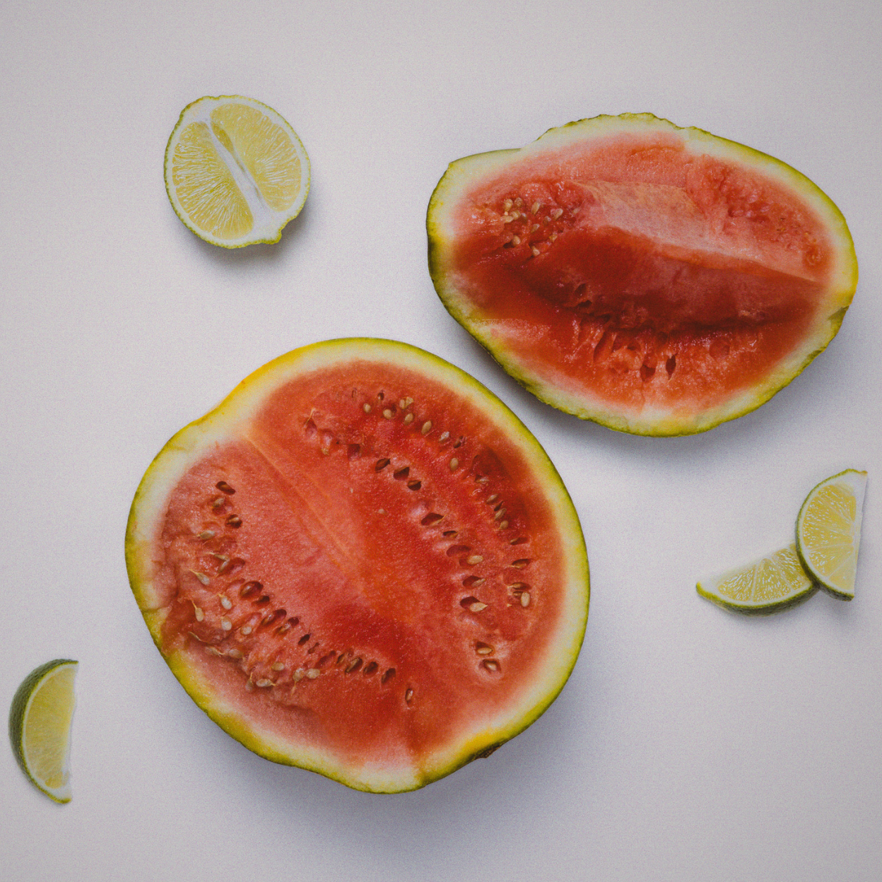 Two halves of a watermelon with lime wedges on a white background